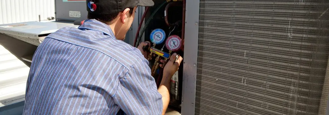 HVAC technician servicing a condenser unit in Covington