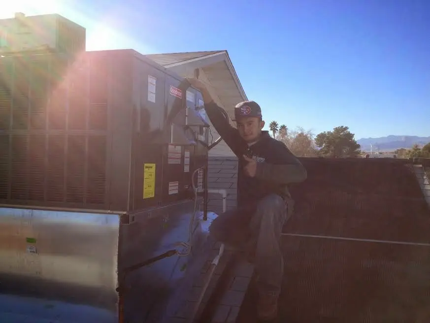 HVAC technician performing Air Duct Cleaning on a rooftop unit in Covington
